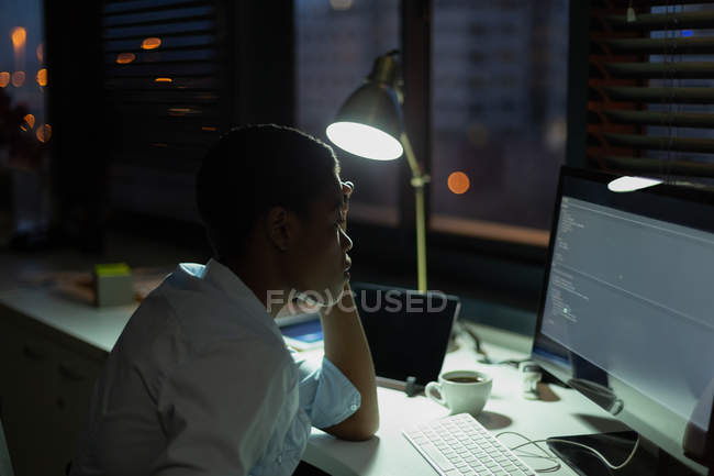 Female executive working at desk in office at night — Stock Photo