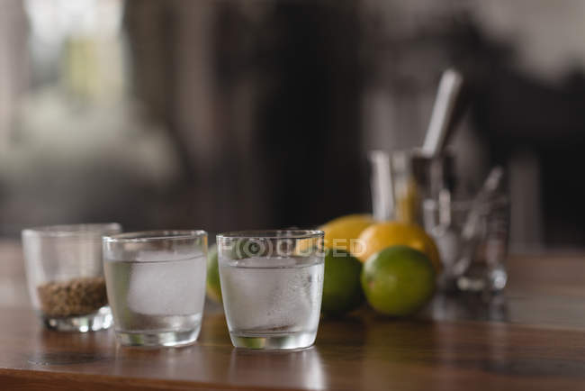 Close-up of citrus fruits, wheat grain and gin with ice in glasses — Stock Photo
