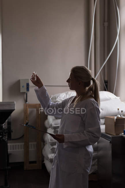 Female worker checking quality of gin in factory — Stock Photo
