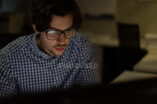 Male executive working at desk in office at night — Stock Photo