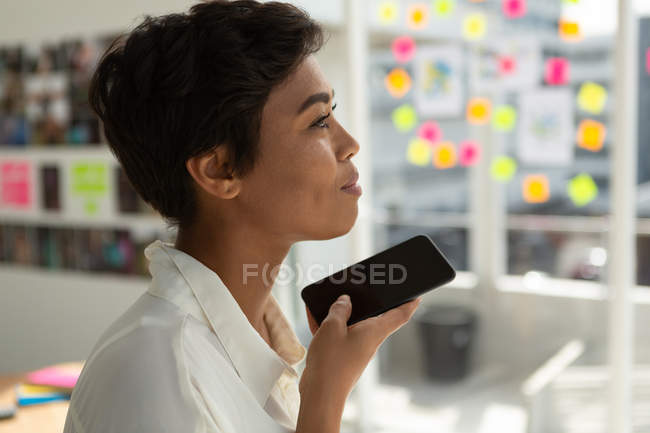 Side view of business executive talking on mobile phone in office. — Stock Photo