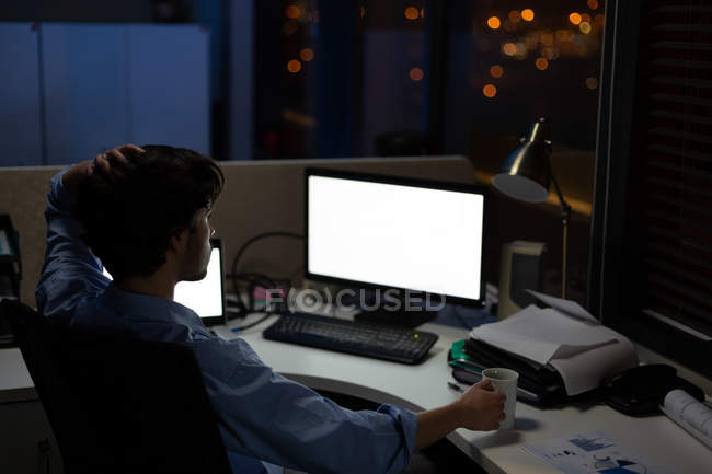 Мужчина-руководитель, работающий за столом в офисе ночью — стоковое фото