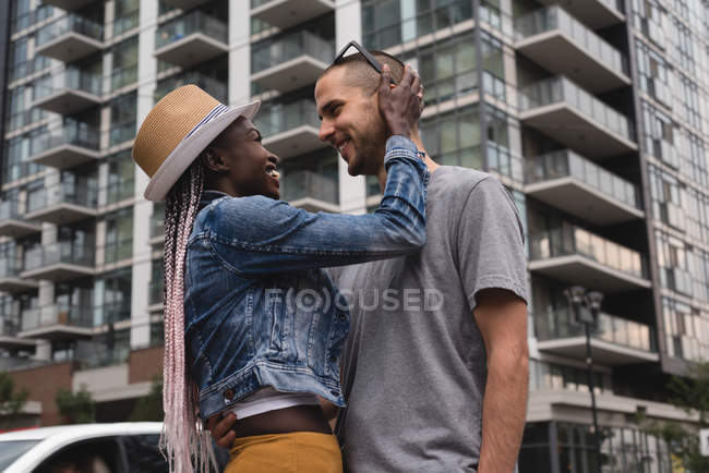 Vista de ángulo bajo de la feliz pareja abrazando en la ciudad - foto de stock