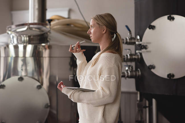 Side view of female worker talking on mobile phone in factory — Stock Photo