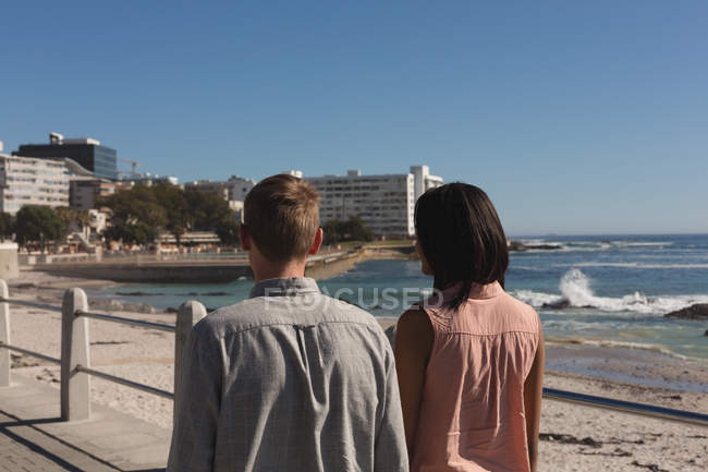Вид ззаду пари, що йдуть на набережній біля пляжу — стокове фото