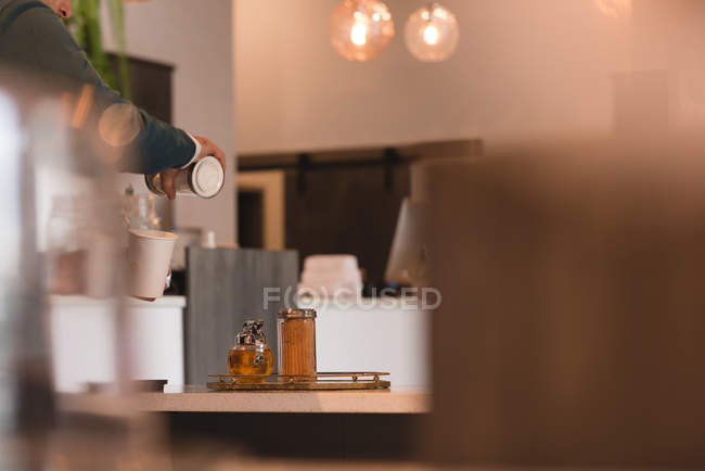 Homem derramando café em xícara no café — Fotografia de Stock