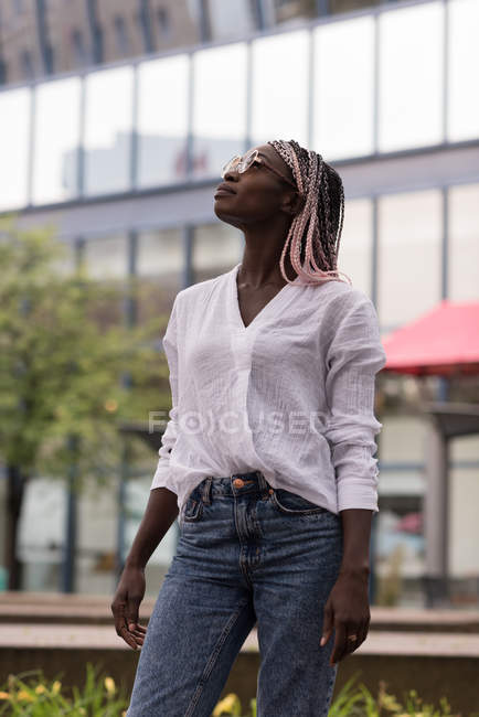 Fashionable young woman in sunglasses looking up — Stock Photo