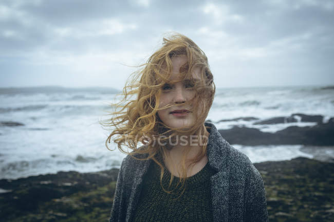 Portrait of redhead woman standing in windy beach. — Stock Photo