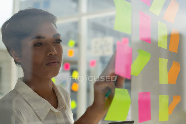 Business executive working on sticky notes in office — Stock Photo