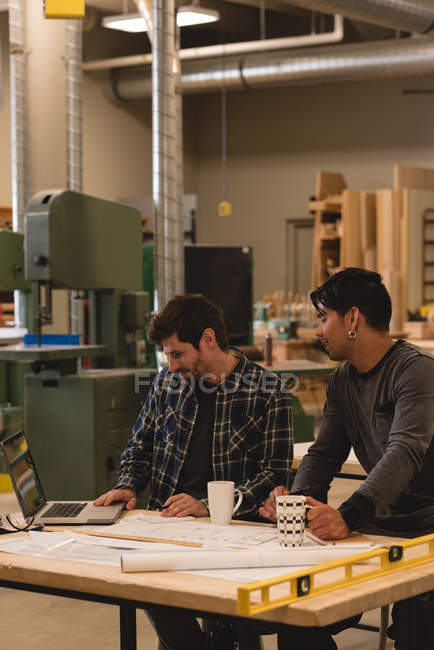 Двоє уважних майстрів використовують ноутбук у майстерні — стокове фото