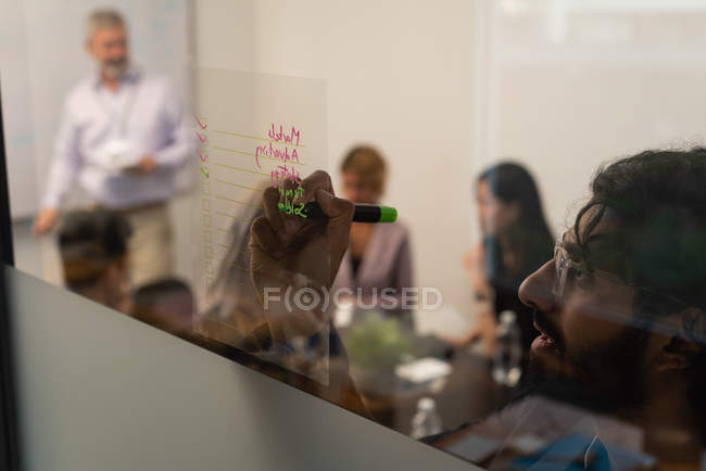 Чоловічий виконавчий писати на скляною стіною в офісі — стокове фото