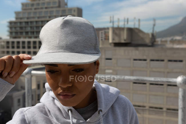 Close-up of casual woman posing in cap on terrace. — Stock Photo