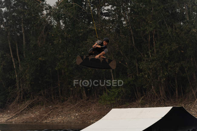 Young athlete wakeboarding in river at dusk — Stock Photo