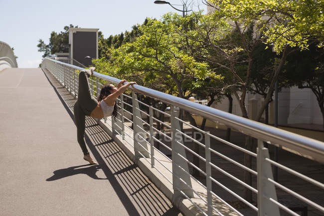 Vista lateral de bailarina urbana practicando danza sobre barandilla de puente . - foto de stock