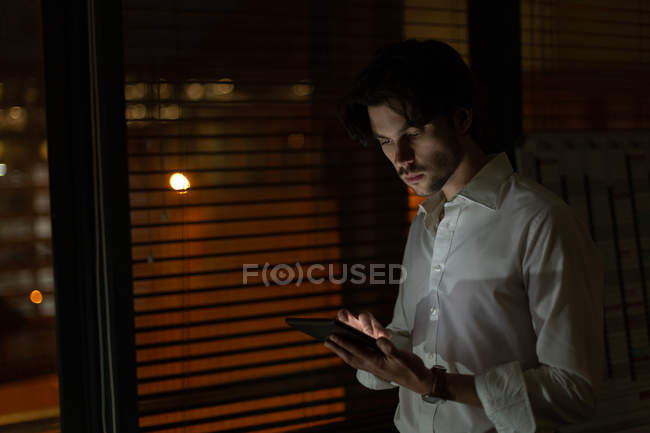 Ejecutivo masculino usando tableta digital en la oficina por la noche - foto de stock