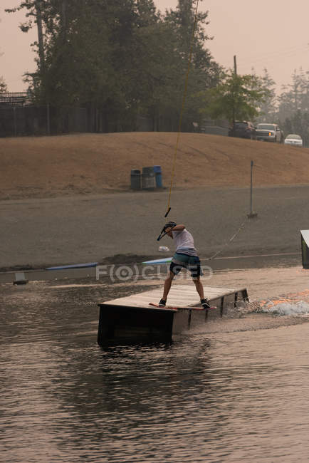 Mid adult man wakeboarding in river water — Stock Photo