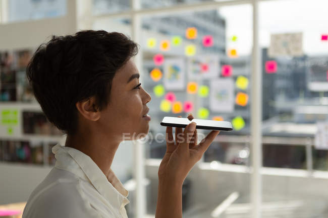 Side view of business executive talking on mobile phone in office. — Stock Photo