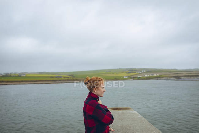 Femme rousse réfléchie debout dans la plage . — Photo de stock