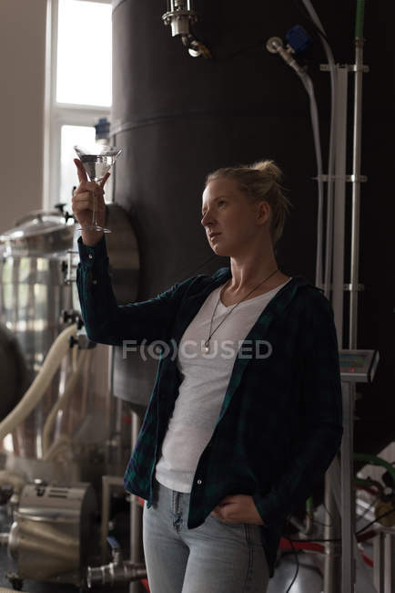 Female worker checking quality of gin in factory — Stock Photo