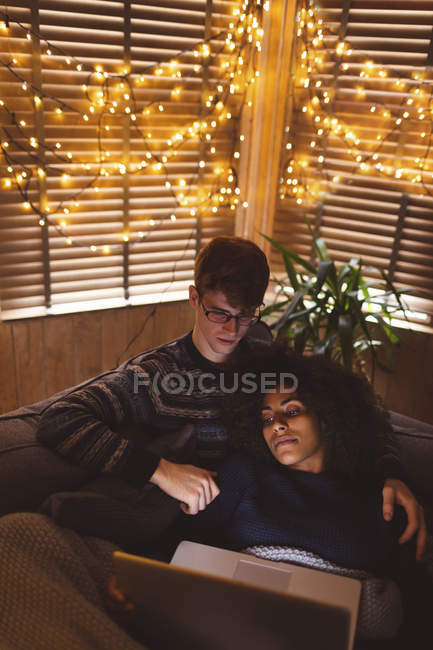 Пара, використовуючи ноутбук у вітальні з фея вогнями на дому — стокове фото