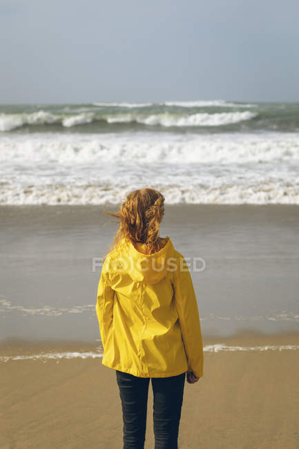 Visão traseira da mulher ruiva em pé na praia . — Fotografia de Stock