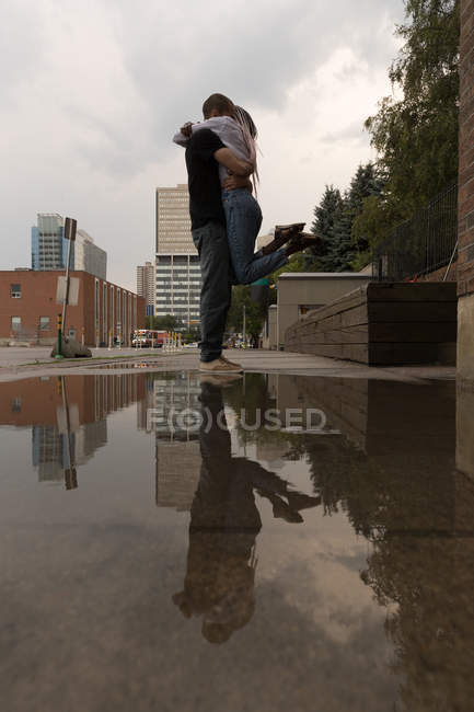 Liebespaar umarmt sich auf Bürgersteig in der Stadt — Stockfoto
