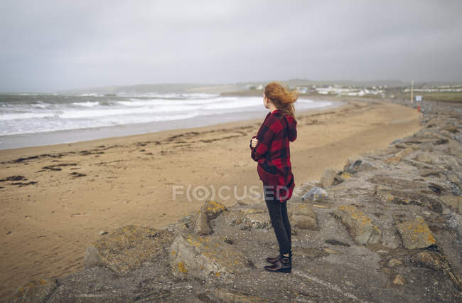 Femme rousse réfléchie debout dans la plage de sable . — Photo de stock