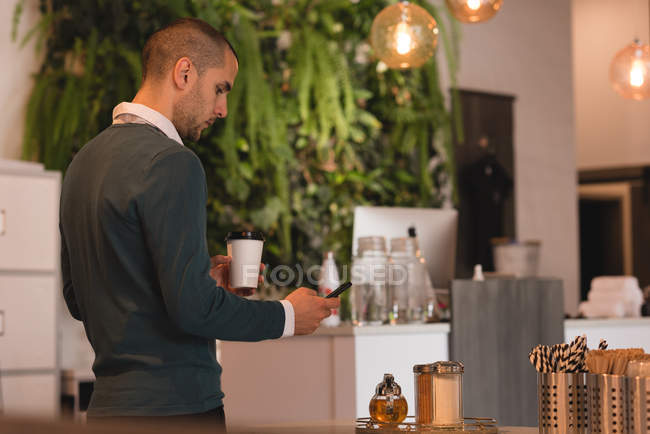 Mann mit Kaffeetasse mit Handy im Café — Stockfoto
