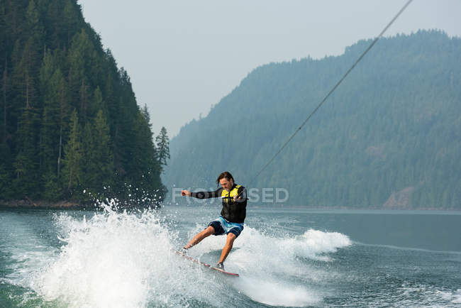 Männlicher Wakeboarder reitet auf Wellen des Waldflusses — Stockfoto