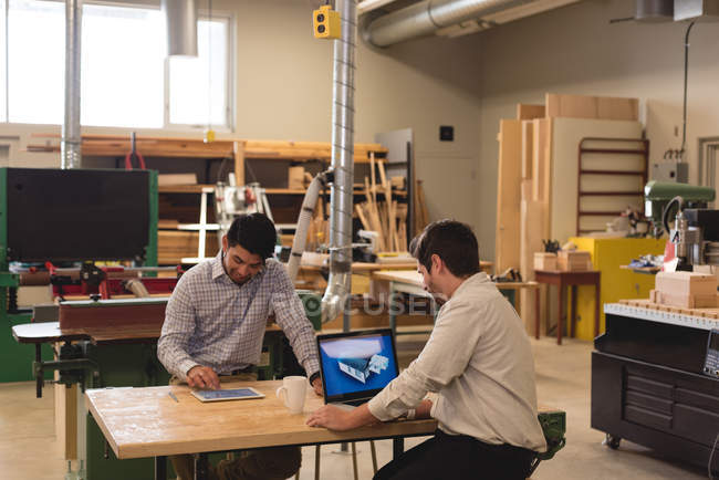Dois artesãos usando tablet digital e laptop na oficina — Fotografia de Stock