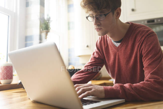 Man using laptop in kitchen at home — Stock Photo