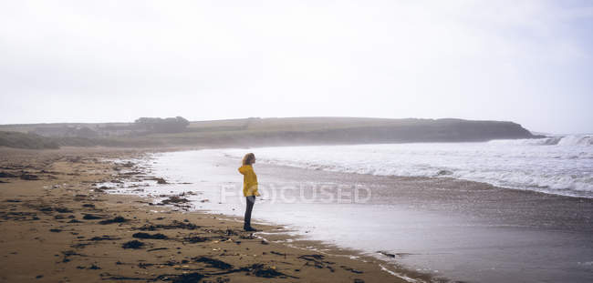 Вид збоку руда жінка стоїть на піщаному пляжі . — стокове фото