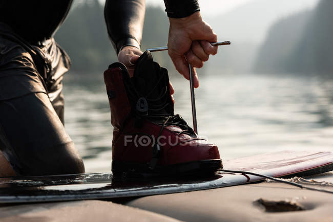 Mid section of man repairing wakeboard at river — Stock Photo