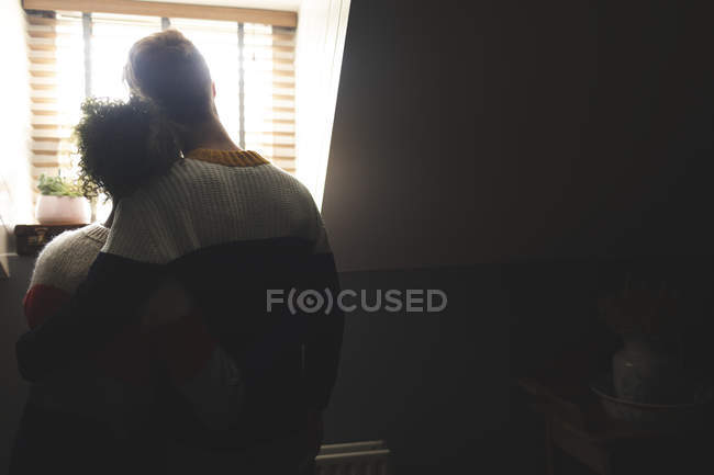 Rear view of couple embracing at home in backlit — Stock Photo