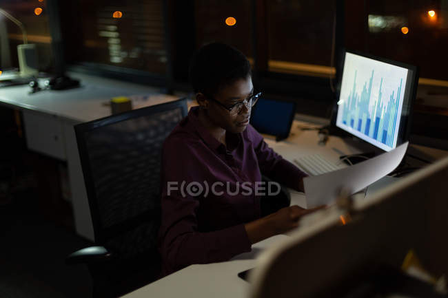 Mujer ejecutiva trabajando en el escritorio en la oficina por la noche - foto de stock