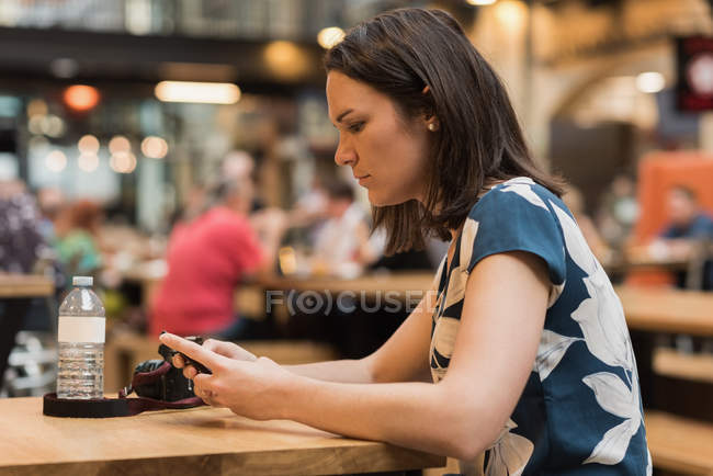 Schöne Frau benutzt Handy in Restaurant — Stockfoto