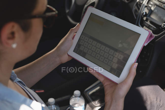 Gros plan de la femme utilisant une tablette numérique dans une voiture — Photo de stock