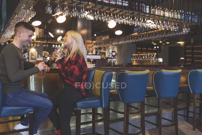 Casal feliz tomando bebidas no balcão do bar — Fotografia de Stock