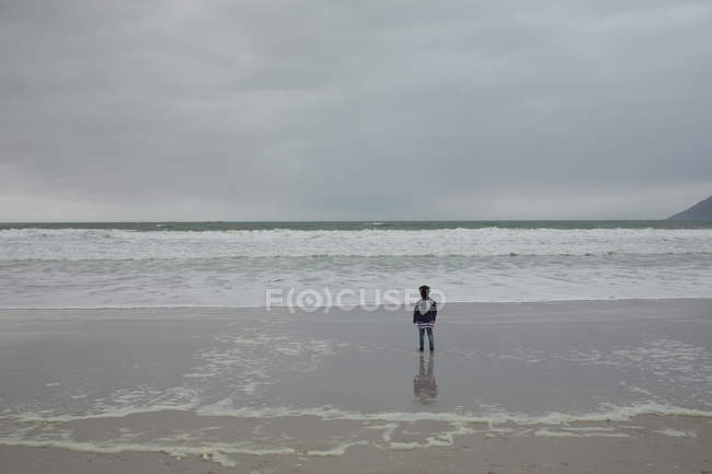 Вид ззаду дівчини, що стоїть на пляжі — стокове фото