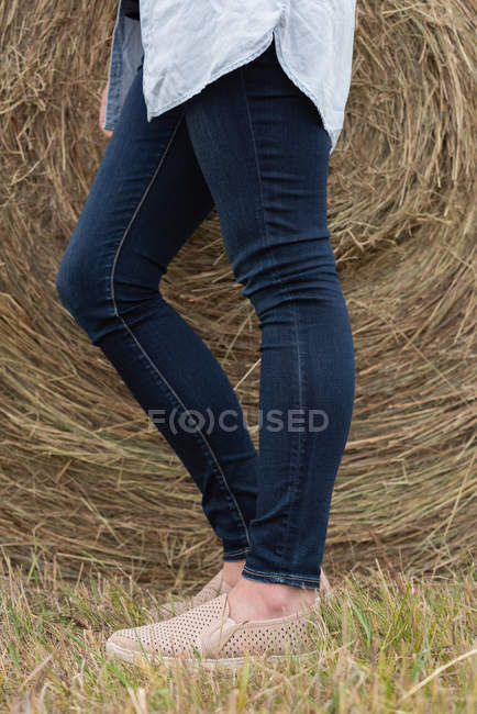 Нижняя часть женщины опирается на тюк сена в поле — стоковое фото