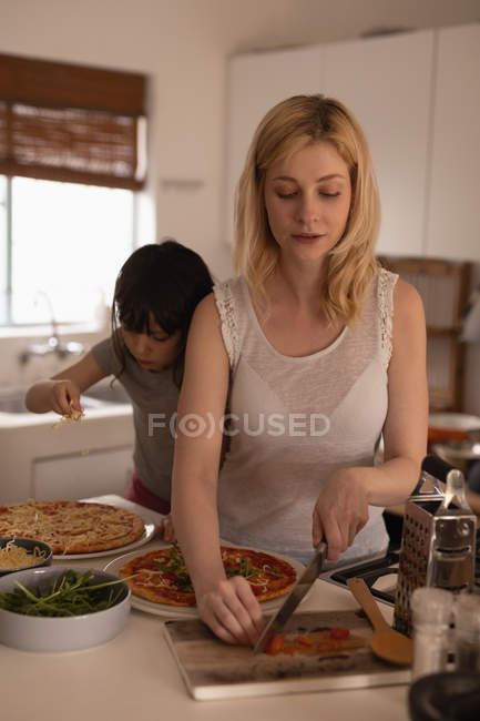 Madre e hija preparando comida en la cocina en casa - foto de stock