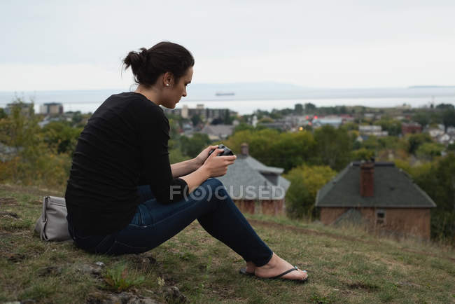 Vista lateral de la mujer revisando fotos en la cámara - foto de stock