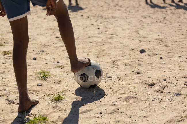 Low section of boy playing football in the ground — Stock Photo