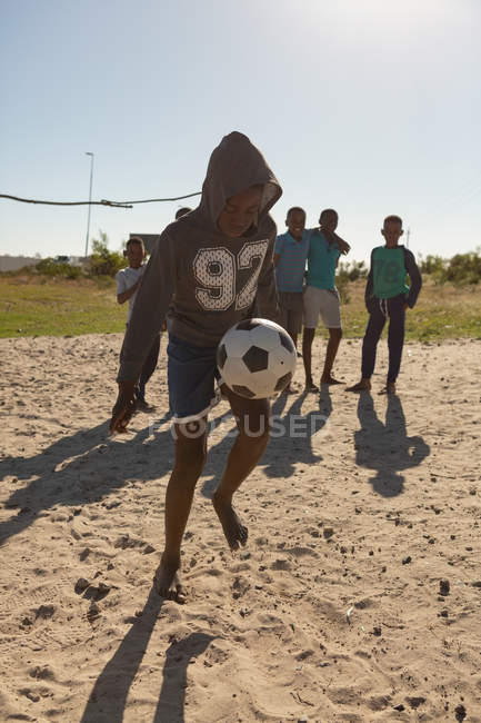 Хлопчик грає у футбол на землі в сонячний день — стокове фото