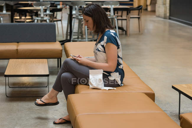 Vista lateral da mulher usando telefone celular no restaurante — Fotografia de Stock