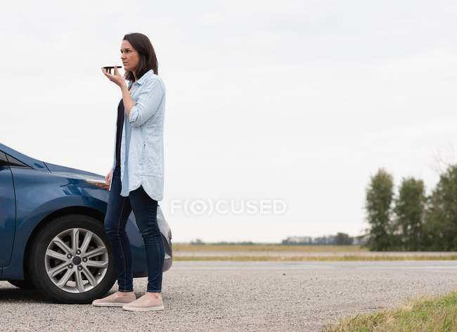 Vista lateral de la mujer hablando en el teléfono móvil durante la avería del coche - foto de stock
