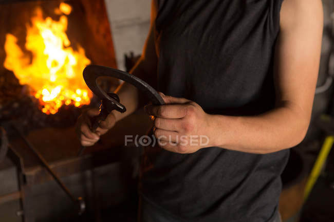 Mid section of female metalsmith molding horseshoe in factory — Stock Photo