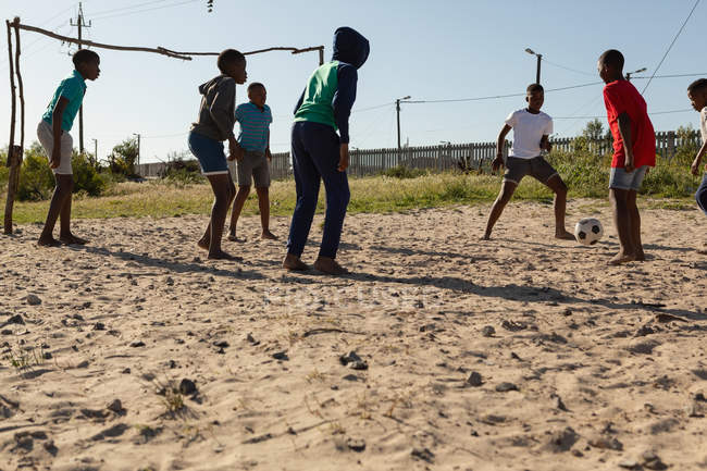 Crianças jogando futebol no chão em um dia ensolarado — Fotografia de Stock