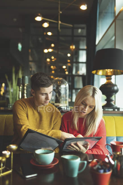 Coppia discutendo sopra scheda menu in caffè — Foto stock