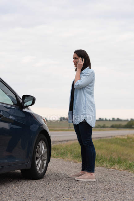 Side view of woman talking on mobile phone during car breakdown — Stock Photo
